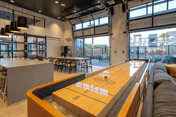A modern bar with a long wooden counter and a large window overlooking the street.